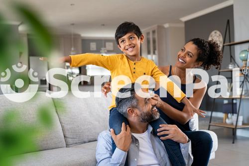 Cheerful Indian Son Sitting On Father Shoulder Playing At Home With African Mother Playful Little Boy Enjoying Spending Time With Parents At Home Flying Child Enjoying Playing With His Ethnic Family