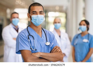 Confident Multiethnic Male Nurse In Front Of His Medical Team Looking At Camera Wearing Face Mask During Covid 19 Outbreak Happy And Proud Indian Young Surgeon Standing In Front Of His Colleagues