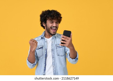 Excited Happy Young Indian Man Winner Feeling Joy Using Smartphone Winning Lottery Game Betting Getting Cashback Online Gift In Mobile App Message Holding Cell Phone Isolated On Yellow Background