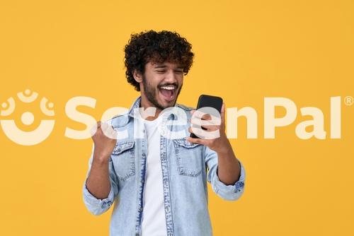 Excited Happy Young Indian Man Winner Feeling Joy Using Smartphone Winning Lottery Game Betting Getting Cashback Online Gift In Mobile App Message Holding Cell Phone Isolated On Yellow Background