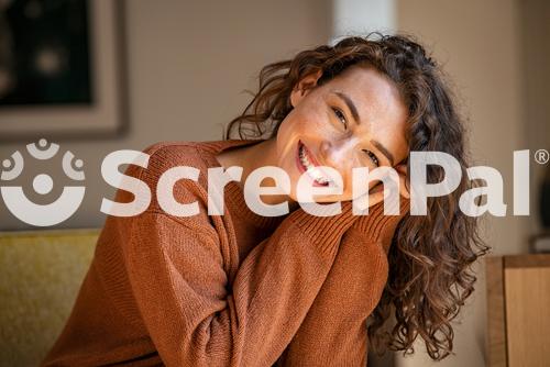 Happy Young Woman Sitting On Sofa At Home And Looking At Camera Portrait Of Comfortable Woman In Winter Clothes Relaxing On Armchair Portrait Of Beautiful Girl Smiling And Relaxing During Autumn