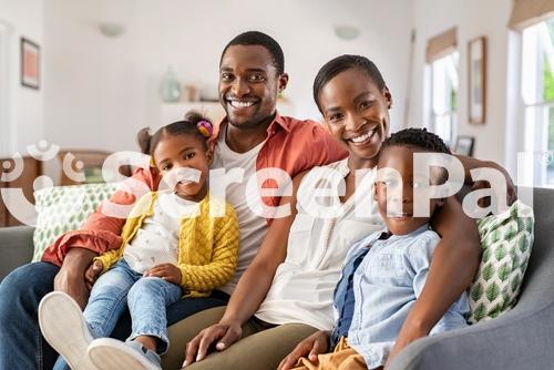 Portrait Of Happy Mature Couple With Son And Daughter Relaxing On Sofa At Home Middle Aged Black Woman With Husband And Children Smiling And Looking At Camera Beautiful Mid African American Family