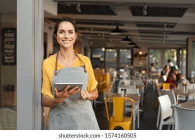 Portrait Of Happy Woman Standing At Doorway Of Her Store Cheerful Mature Waitress Waiting For Clients At Coffee Shop Successful Small Business Owner In Casual Wearing Grey Apron Standing At Entrance