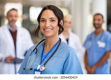 Portrait Of Happy Young Nurse In Uniform With Healthcare Team In Background Successful Team Of Doctor And Nurses Smiling Beautiful And Satisfied Healthcare Worker In Private Clinic Looking At Camera