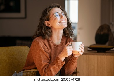 Portrait Of Joyful Young Woman Enjoying A Cup Of Coffee At Home Smiling Pretty Girl Drinking Hot Tea In Winter Excited Woman Wearing Spectacles And Sweater And Laughing In An Autumn Day