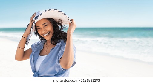 Portrait Of Stylish Latin Hispanic Woman With White Straw Hat Standing At Beach Young Smiling Woman On Vacation Enjoy Sea Breeze Wearing Straw Hat And Looking At Camera Attractive Beautiful Girl