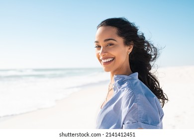 Portrait Of Young Woman At Sea Looking At Camera Smiling Latin Hispanic Girl Standing At The Beach With Copy Space And Looking At Camera Happy Mixed Race Girl In Casual Outfit With Wind In Her Hair