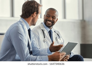 Two Mature Smiling Doctors Having Discussion About Patient Diagnosis Holding Digital Tablet Representative Pharmaceutical Discussing Case After Positive Result With Happy Doctor About New Medicine