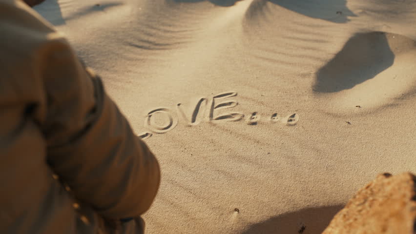 A Girl In The Sand Draws The Word Love Girl Draws A Symbol Of The Heart And Love On The Sandy Beach Rear View Close Up The Concept Of Love 4k