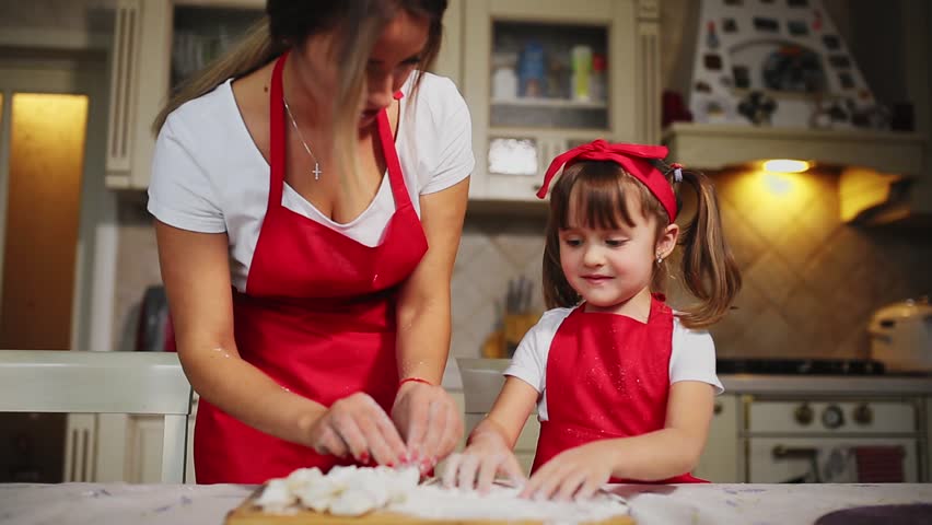 Happy Family In The Kitchen Mom And Daughter In The Kitchen Playing With Flour To Have Fun And Mold The Patties In The Kitchen In The Same Red Aprons Stedicam