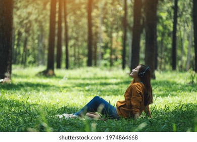 A Beautiful Young Asian Woman Enjoy Listening To Music With Headphone With Feeling Happy And Relaxed In The Park