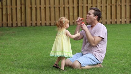 Father Blowing Bubbles For Her Daughter