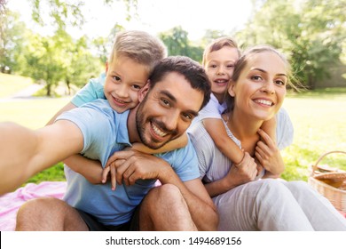 Family Leisure And Technology Concept   Happy Mother Father And Two Little Sons Having Picnic And Taking Selfie At Summer Park