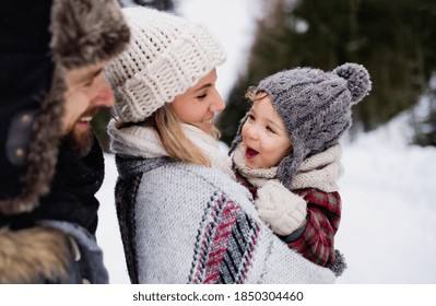 Father And Mother With Small Child In Winter Nature Standing In The Snow