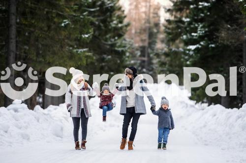 Father And Mother With Two Small Children In Winter Nature Walking In The Snow