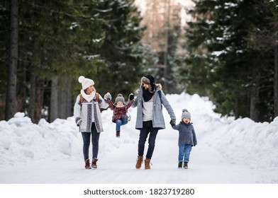 Father And Mother With Two Small Children In Winter Nature Walking In The Snow