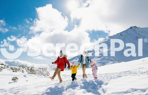 Father And Mother With Two Small Children In Winter Nature Walking In The Snow