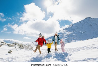 Father And Mother With Two Small Children In Winter Nature Walking In The Snow