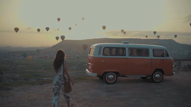 A View Of Hot Air Balloons In The Air And Woman Riding Her Vehicle