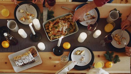 A Person Slicing A Roasted Turkey Served In A Dining Table