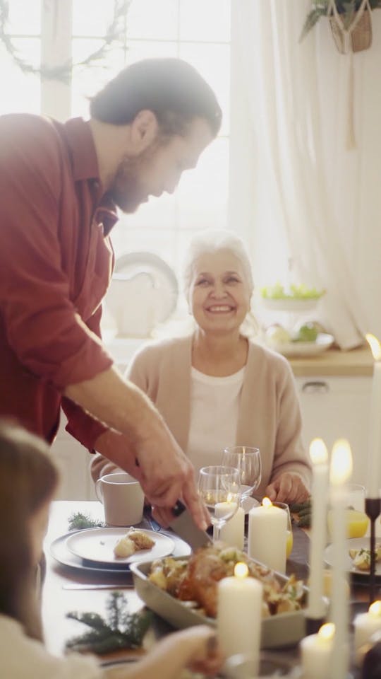 A Man Slicing A Roasted Turkey Served In A Family Dinner