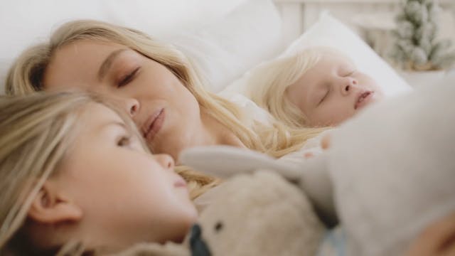 A Mother Loving Moments With Her Two Children Lying In Bed Together