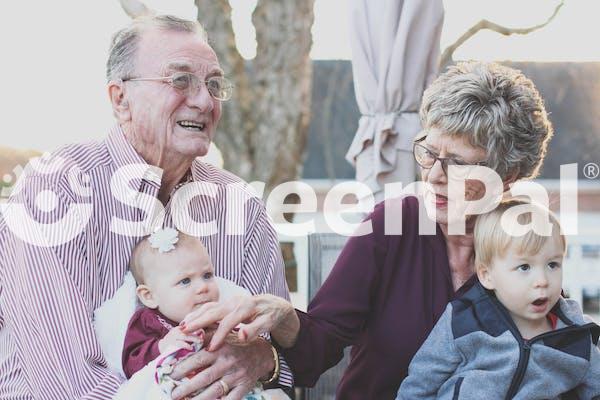 Grandmother And Grandfather Holding Child On Their Lap