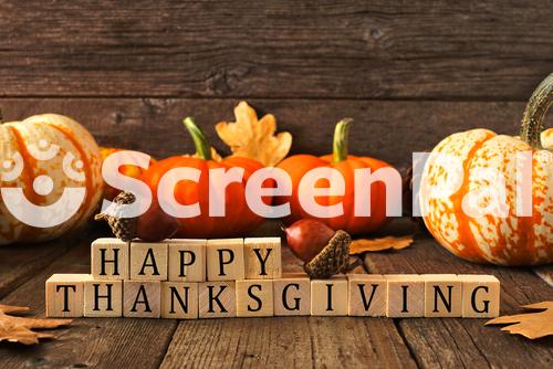 Happy Thanksgiving Greeting On Wooden Blocks Against A Rustic Wood Background With Pumpkins And Autumn Leaves