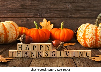 Happy Thanksgiving Greeting On Wooden Blocks Against A Rustic Wood Background With Pumpkins And Autumn Leaves