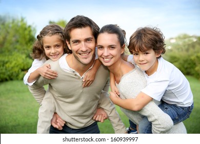 Parents Giving Piggyback Ride To Children