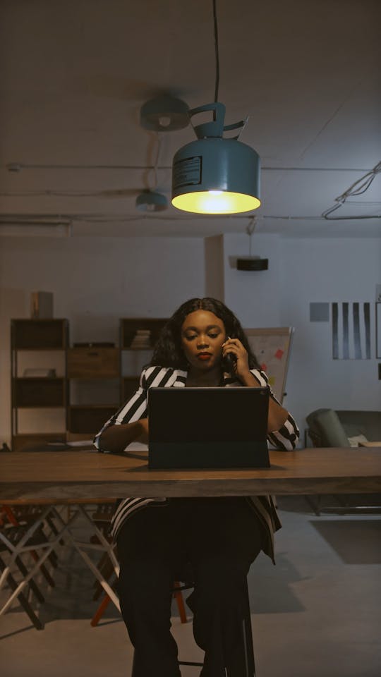 Woman Using Laptop And Talking On Phone