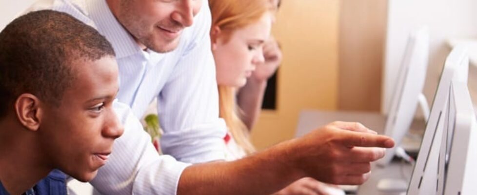 Image of teacher showing student how to do something on a computer