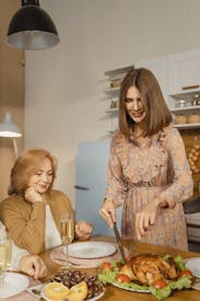 Woman In Brown And White Floral Long Sleeve Shirt Sitting Beside Woman In Brown Coat